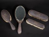 trois brosses à cheveux anciennes et un miroir posés sur un support noir