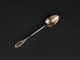 a silver spoon with a gold handle sitting on a black surface