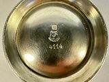 a silver plate on a stand on a white surface
