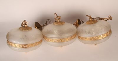 three white and gold glass ornaments on a white surface