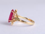 a close up of a gold ring with a pink stone