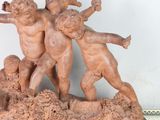 a statue of three children playing with a ball on a table