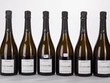 six bouteilles de vin sont alignées sur une surface blanche