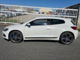 La voiture blanche est garée devant une clôture blanche.