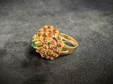 an image of a gold ring with red and green stones on it