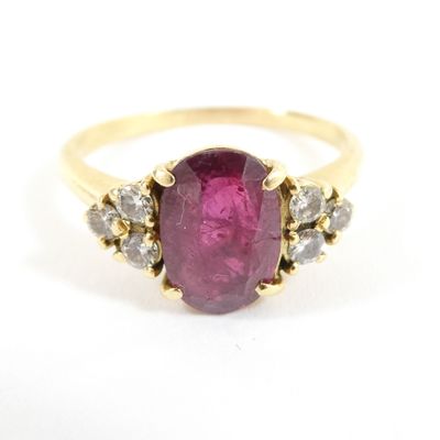 a close up of a ring with a pink stone surrounded by diamonds