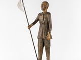 a wooden statue of a man holding a spear and a flag