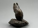 statue d'une souris assise sur une feuille posée sur une surface blanche