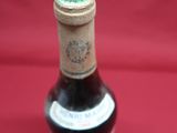 an old bottle of wine sitting on top of a red cloth