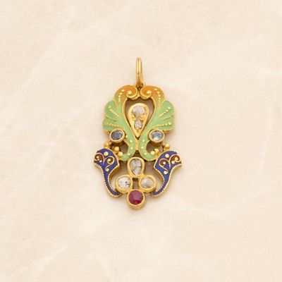 a gold pendant with a bird and a flower design on it