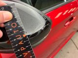 a hand that is holding a measuring tape in front of a red car
