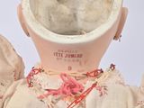 a doll that is wearing a white dress and a pink hat