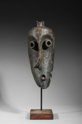 une image représentant un masque en bronze posé sur un socle en bois