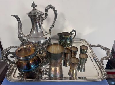 un plateau en argent sur lequel sont posés une théière et des tasses en argent