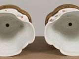 pair of white porcelain vases with floral designs on them