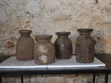 quatre vases posés sur une table devant un mur de briques