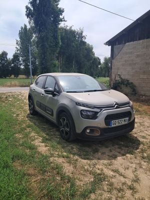 une voiture argentée garée devant un immeuble, sur un chemin de terre