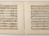an open book with music notes on it sitting on a table