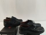 two pairs of black shoes sitting on top of boxes on a white surface