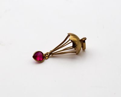 un gros plan d'une boucle d'oreille en or sertie d'une pierre rouge