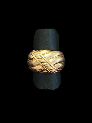 une image montrant un gros plan d'une bague en or posée sur une surface noire