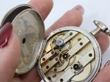 a person holding a silver pocket watch in their hand