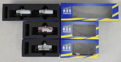 trois boîtes contenant des trains miniatures posées sur une surface blanche