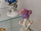 three glass shelves with figurines of birds and flowers on them