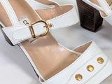 a pair of white shoes with gold buttons on them