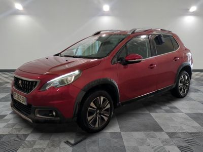 une voiture rouge est garée dans une pièce au sol en damier