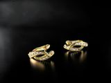 a pair of gold earrings with diamonds on a black background