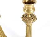 two gold candlesticks sitting next to each other on a white surface