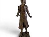 bronze statue of a man with a hat and coat on a base