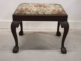 a small wooden bench with a floral cushion on it