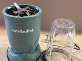 un petit mixeur posé sur un plan de travail, à côté d'une tasse