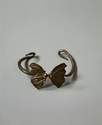 a close up of a metal cuff with a butterfly on it