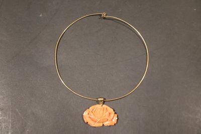 une photo d'un collier orné d'une fleur, posé sur une table