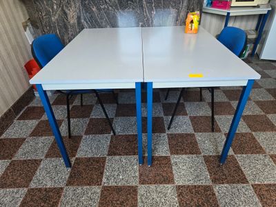 une table blanche et des chaises bleues dans une pièce au sol en damier