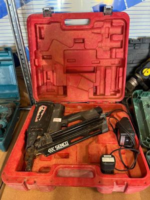 une boîte à outils rouge contenant un pistolet à clous et d'autres outils