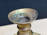 a metal candle holder on a table with a blue wall in the background