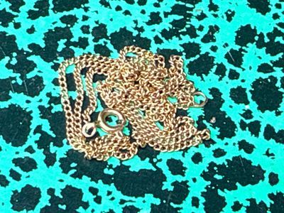 a gold chain with a heart on it sitting on a green surface