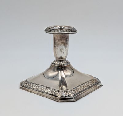 un bougeoir ancien en argent, orné d'un motif raffiné sur fond blanc