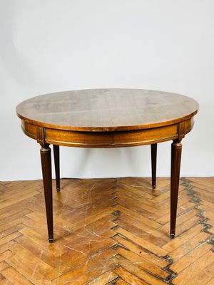 une table à manger ovale avec un plateau en bois, posée sur un parquet