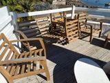 a wooden table and chairs on a deck overlooking the water