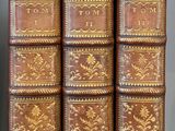 Quatre vieux livres sont alignés sur une étagère dans une pièce
