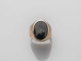 a gold and black stone ring on a white surface