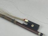 a violin with a wooden case and a long stick