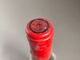 a close up of a bottle of wine with a red cap