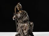 statue d'une femme tenant un bâton, posée sur une surface blanche