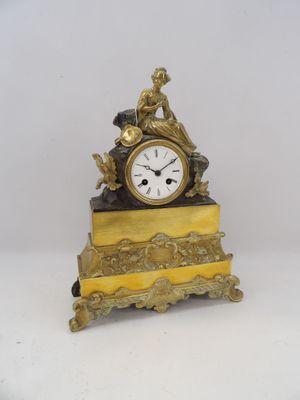 une petite horloge en or surmontée d'une statuette